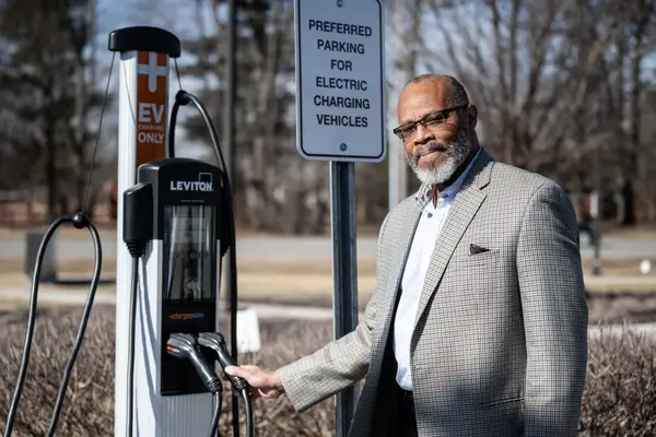 John Morrow Jr. poses next to one of the EV charging stations he helped secure the contract for outside of the Indianapolis Public Library Eagle Branch, Feb. 14, 2025. (Photo/Nate Pappas for Mirror Indy