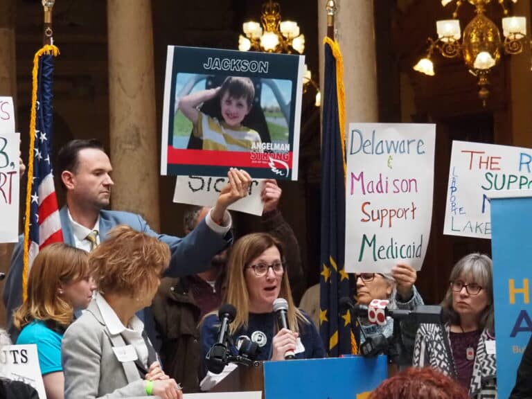 Amanda Moore, at microphone, shares the story of her son Jackson, who depends on Medicaid to cover life-saving treatments for his rare disease. (Photo/Whitney Downard of Indiana Capital Chronicle)