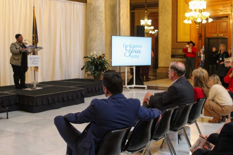 Lt. Gov. Micah Beckwith, and Gov. Mike Braun and his wife Maureen, sat in the front row of an event to commemorate the 25th anniversary Indiana’s Safe Haven law, which allows parents to surrender their infant to a first responder. Marion County Coroner Alfarena T. McGinty (at the podium) said, “The law has not only saved lives, but has given dignity, identity and compassion to the tiniest among us.” (Photo/Sydney Byerly)