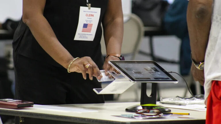 A poll worker for the Marion County Clerk's Office checks a voter's identification card during the May 2024 primary election. (Photo/Lauren Chapman for Indiana Public Broadcasting)